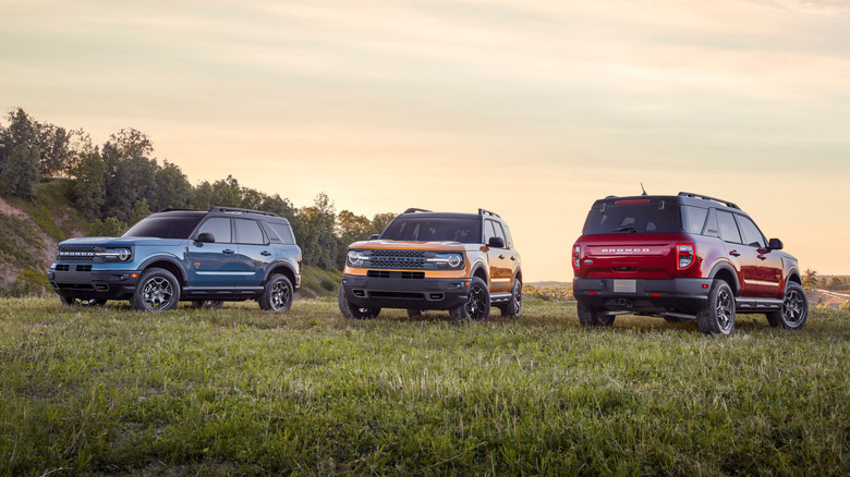 Blue, yellow, and red 2021 Ford Broncos parked on grass