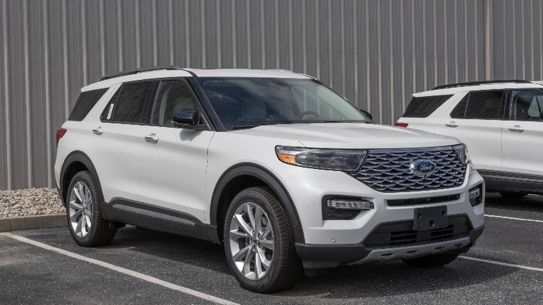 A White Ford Explorer SUV parked in front of a grey wall