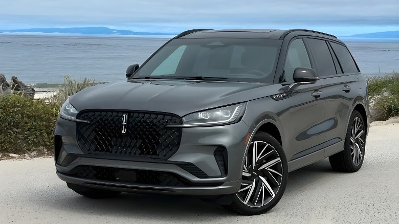 A Dark Grey Lincoln Aviator SUV parked on a road by a beach