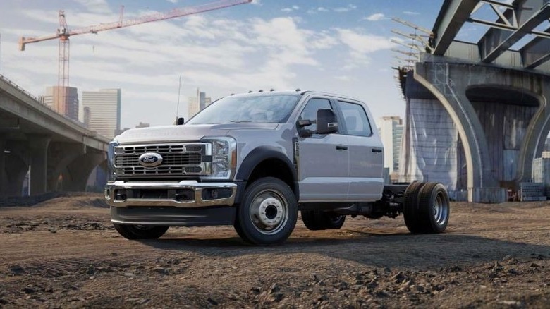 Oxford white Ford Super Duty Chassis Cab parked at a bridge construction site with buildings in the background