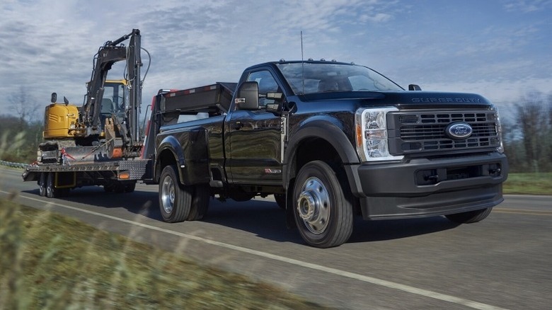 Ford Super Duty towing with green grass on the sides of the road and blue sky in the background