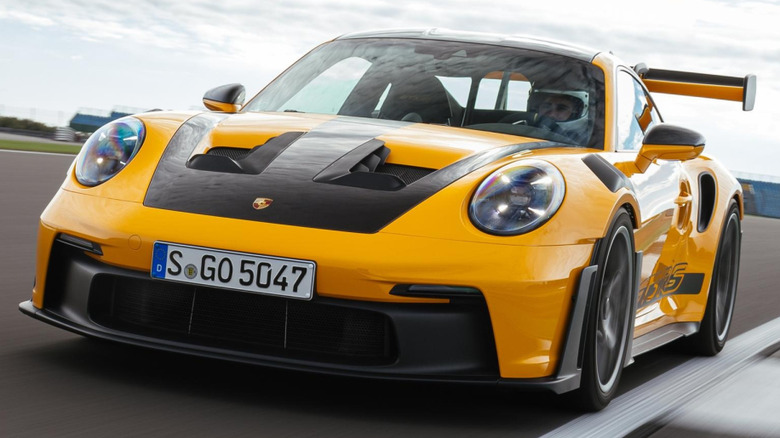 A yellow Porsche 911 GT3 RS (Type 992) with black accents on a racetrack.