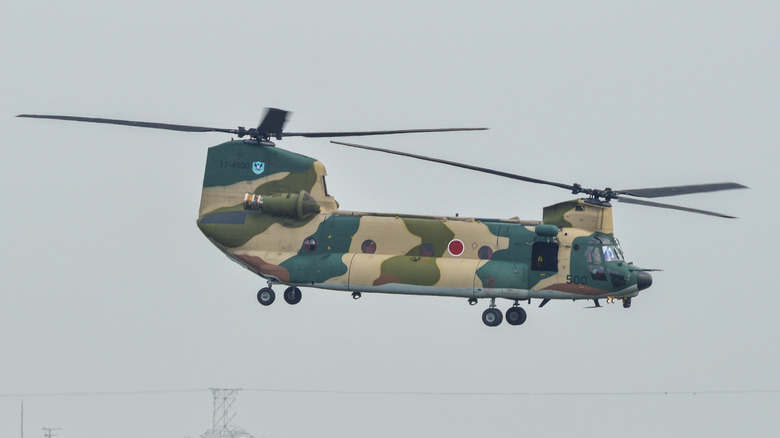 A side view of the Kawasaki CH-47J helicopter with a camouflage pattern in flight