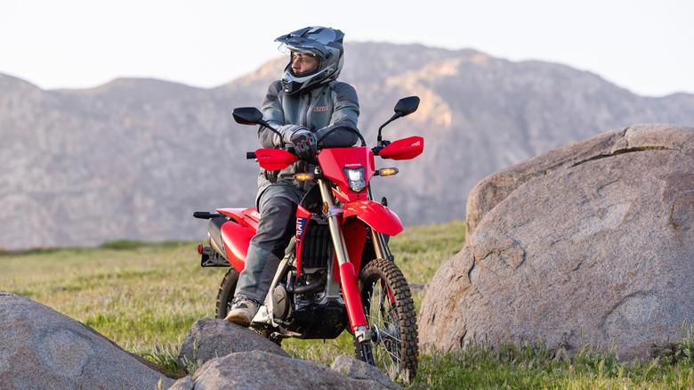 A bike rider staring away from the camera while sitting on a dirt bike