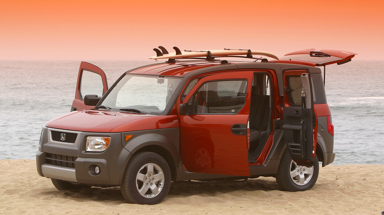 Red 2003 Honda Element parked on a beach with all doors opened