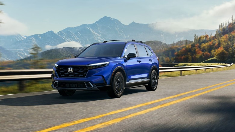 2025 Honda CR-V Sport Touring Hybrid driving on a road with mountains in the background