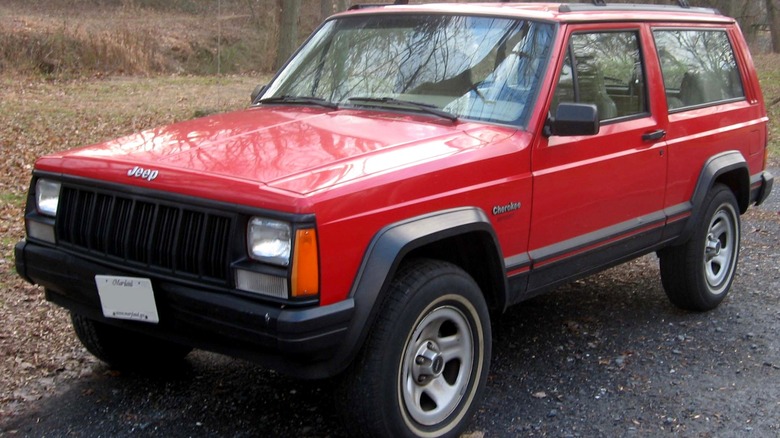 Red Jeep Cherokee XJ parked on gravel