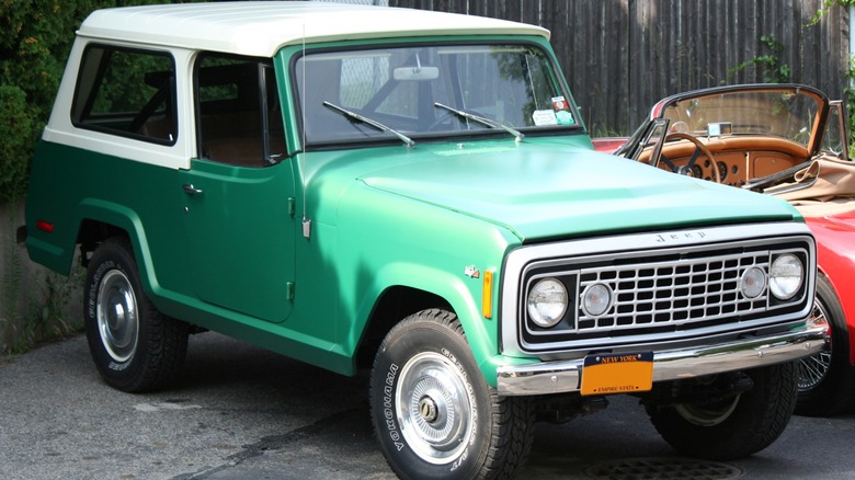 Green Jeep Commando parked next to a red convertible