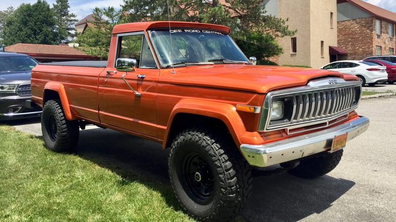 Orange Jeep J-20 parked near buildings