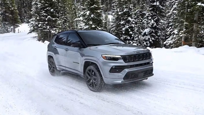 Jeep Compass driving on snow-covered road in winter with trees in the background