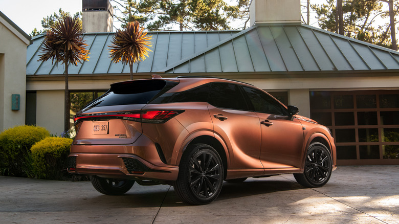 2024 Lexus RX 500h F Sport Performance copper body color parked on a driveway rear 3/4 view