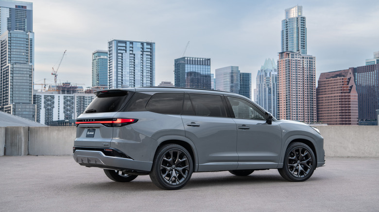 2024 Lexus TX 500h F Sport Performance rear 3/4 view with a cityscape in the background