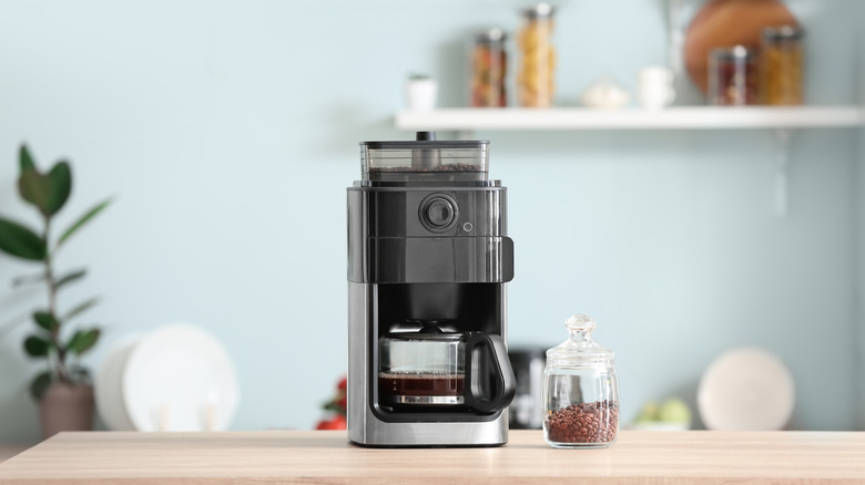 black coffee maker on countertop with jar of coffee beans