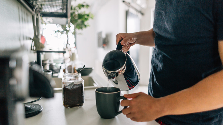 man pouring coffee from coffee maker in kitchen