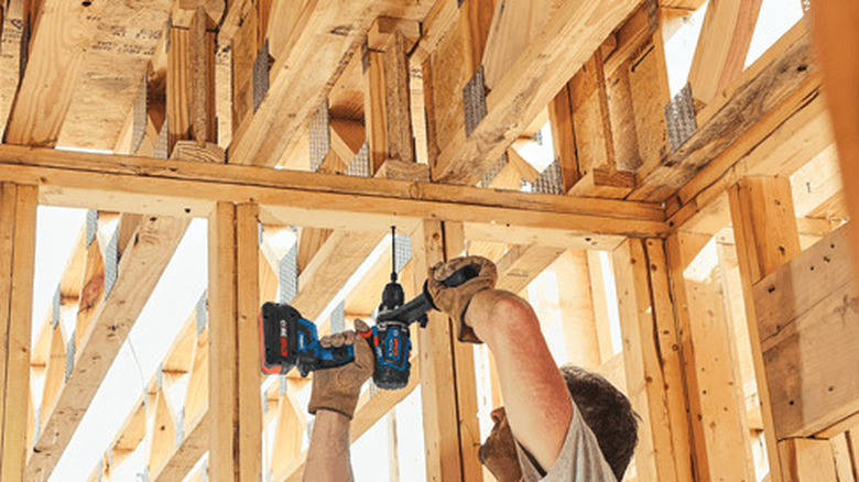 Man drilling up into framing