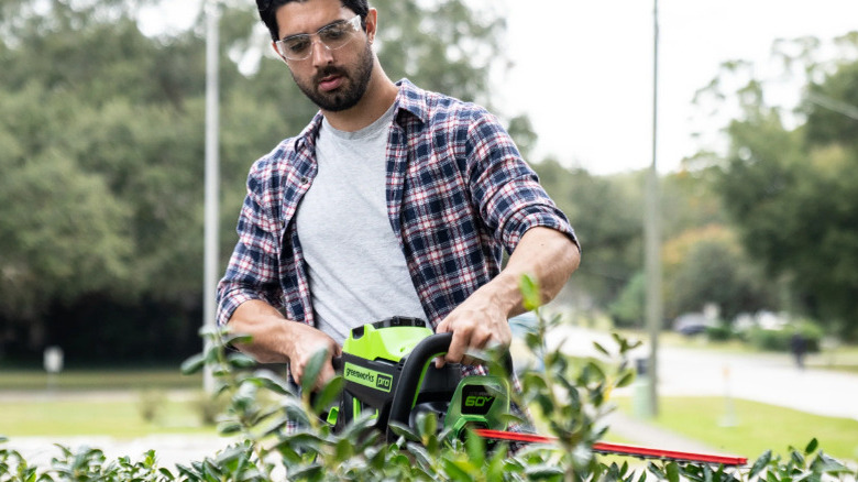 person using hedge trimmer