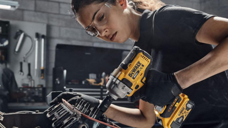 Woman using DeWalt impact wrench on engine