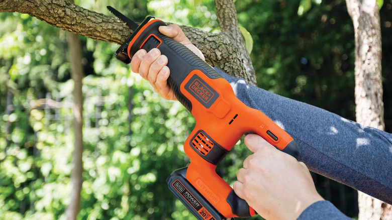 Hands holding a Black + Decker cordless reciprocating saw