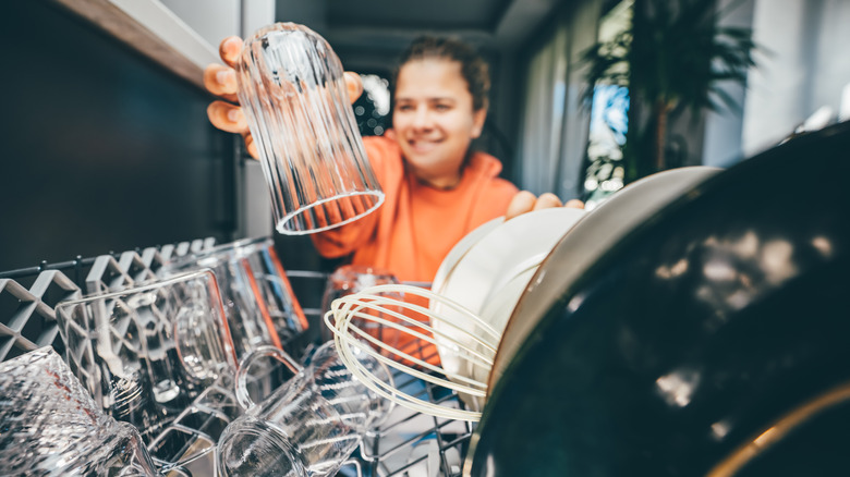 blured woman loading in focus dishwasher