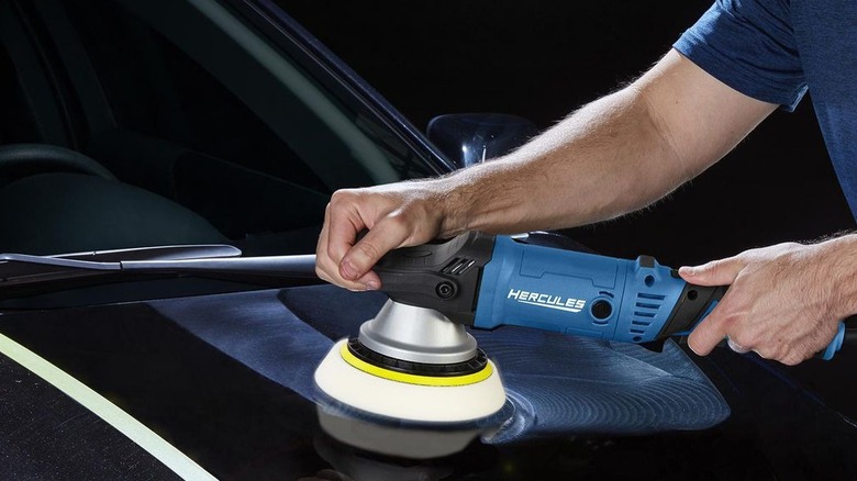 Person using polisher on a dark car hood