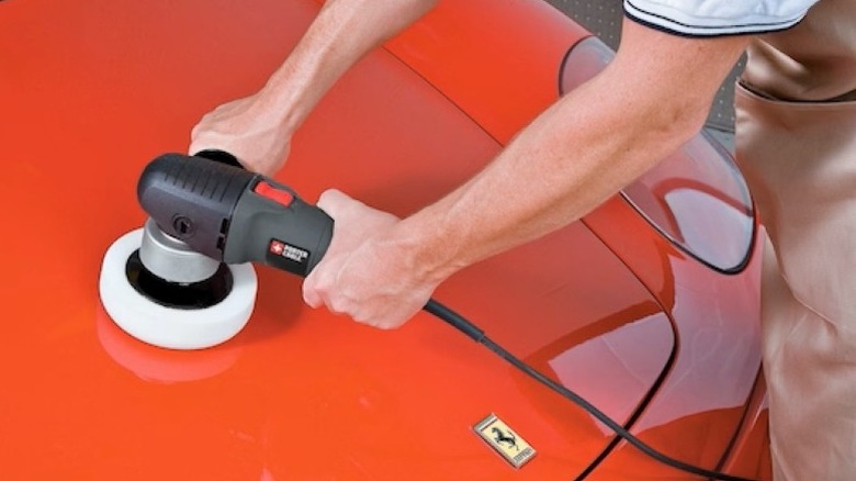 Person using polisher on a red Ferrari