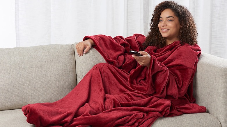 Person with the Sharper Image Heated Wearable Blanket on a couch.