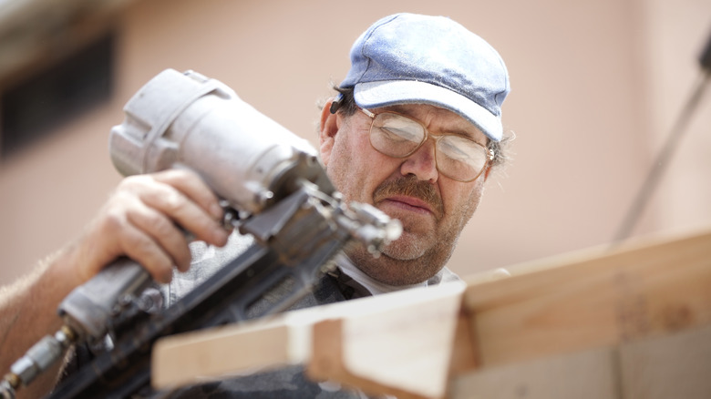 Man using framing nailer on lumber