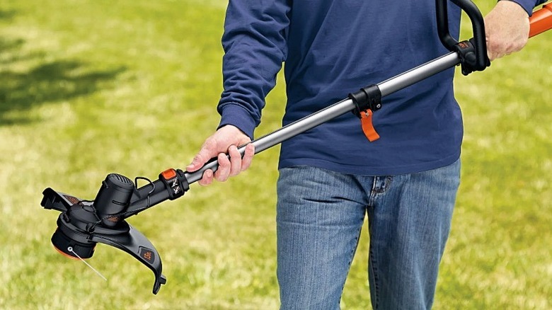 A man holding a B+D grass trimmer in both hands.