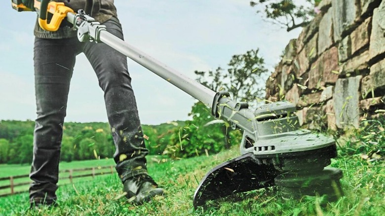 A DeWalt string trimmer tackling some grass.