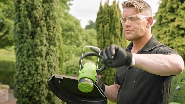 A man holding a Greenworks string trimmer