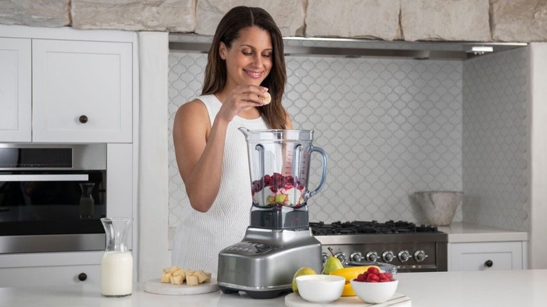 Person putting fruit in a Breville blender