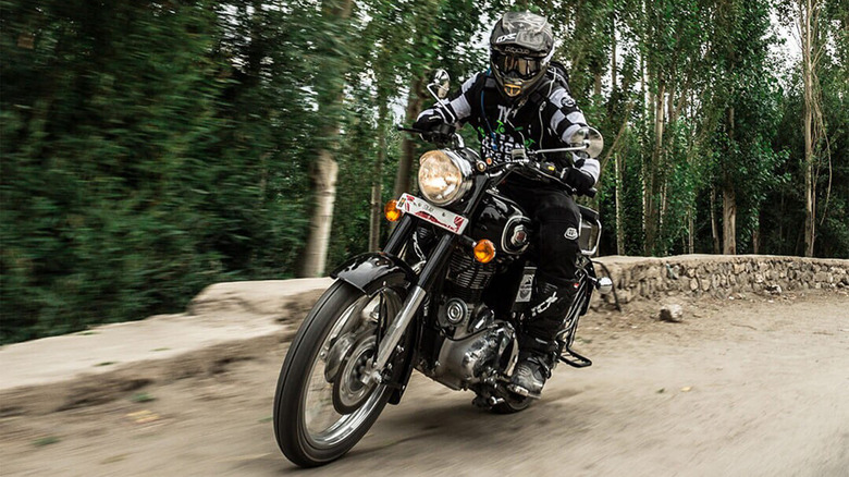 A Royal Enfield Bullet 500 being driven on a dirt road