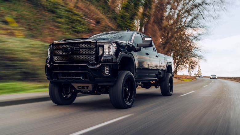 A black GMC Sierra driving down the road