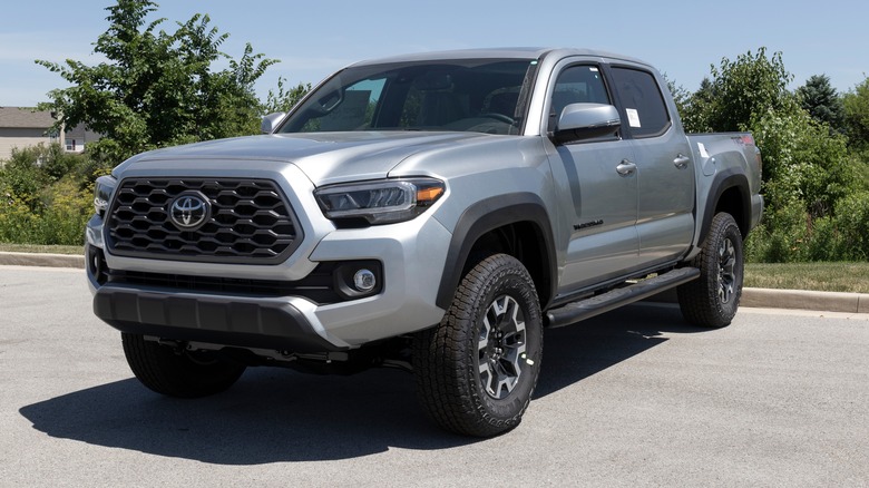 A gray Toyota Tacoma parked in front of bushes