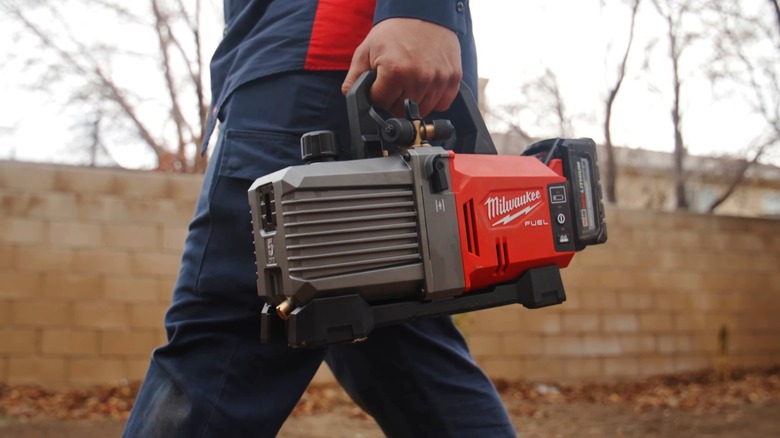 construction worker using a nail gun to put nails in a wall