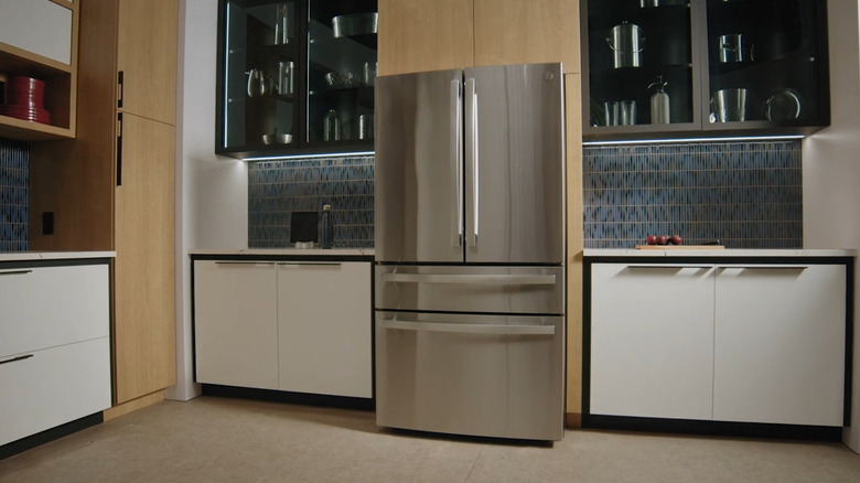 A shiny silver fridge in a white and wood kitchen