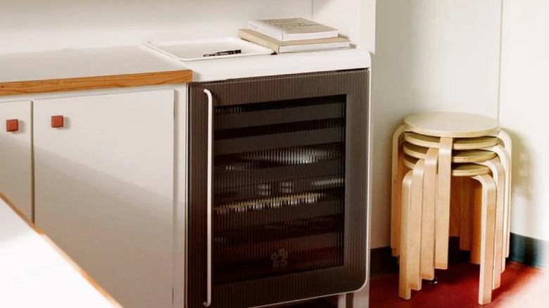 A mini fridge set next to a while cabinet