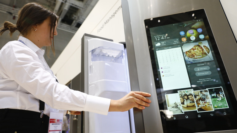 Person opening fridge with screen on door