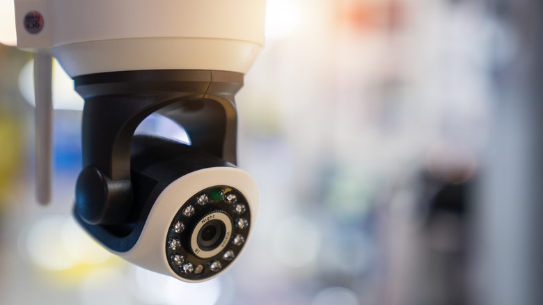 A security camera mounted on the ceiling on a blurry background.