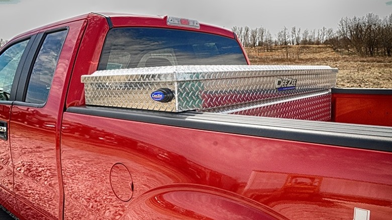 Silver truck bed toolbox mounted in a red pickup