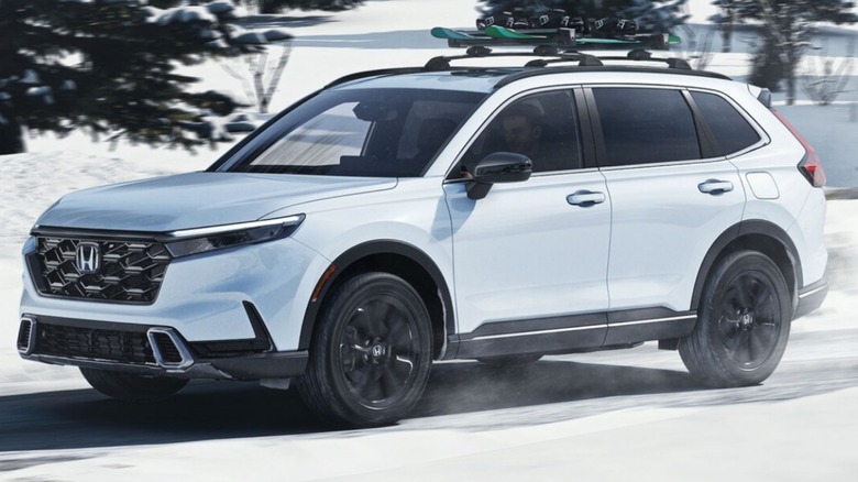 A 2025 Honda CR-V Hybrid driving on a snowy road.