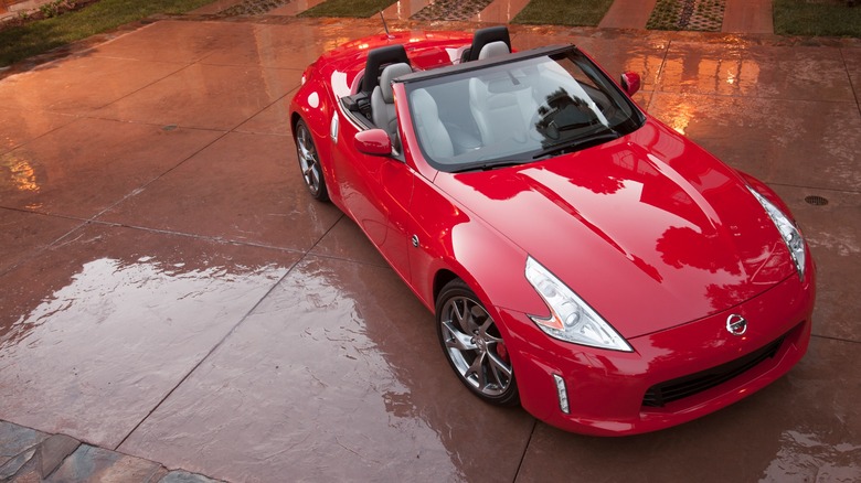 Red Nissan 370Z Roadster with top down parked on wet ground