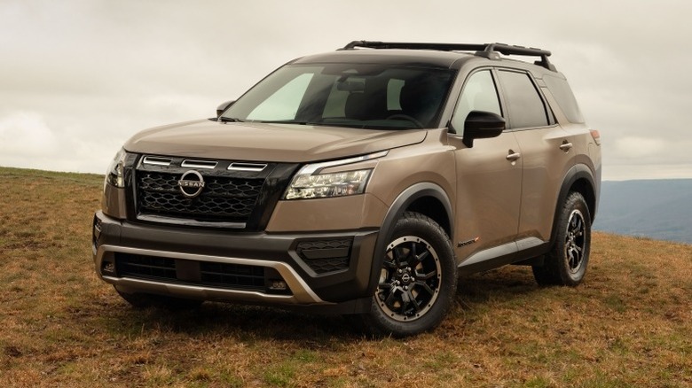 Nissan Pathfinder parked on mountain top with a cloudy sky in the background