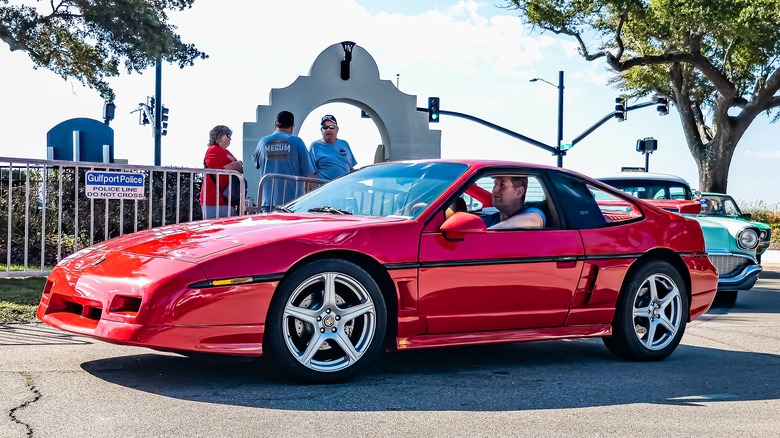 Red Pontiac Fiero GT with a man behind the wheel