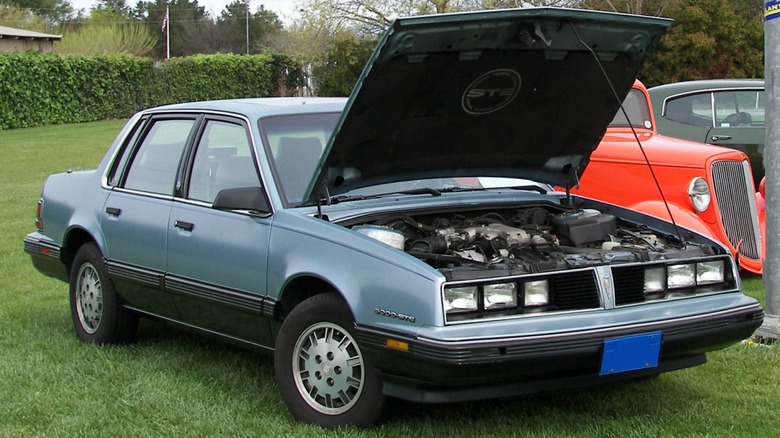 Blue Pontiac 6000 STE parked on grass with hood open