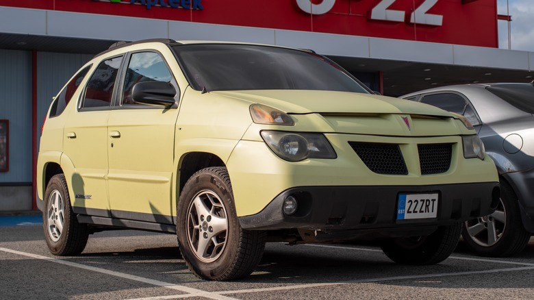 Yellow Pontiac Aztek parked in front of a store