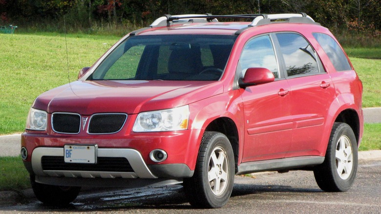 Red Pontiac Torrent parked in front of grass