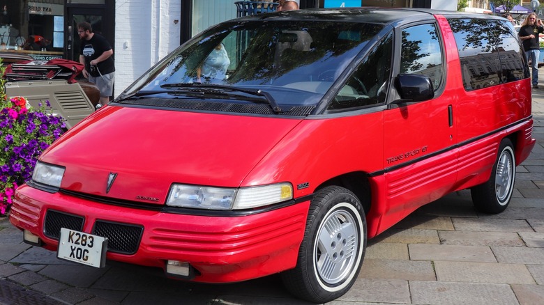 Red Pontiac Trans Sport GT parked in front of shops