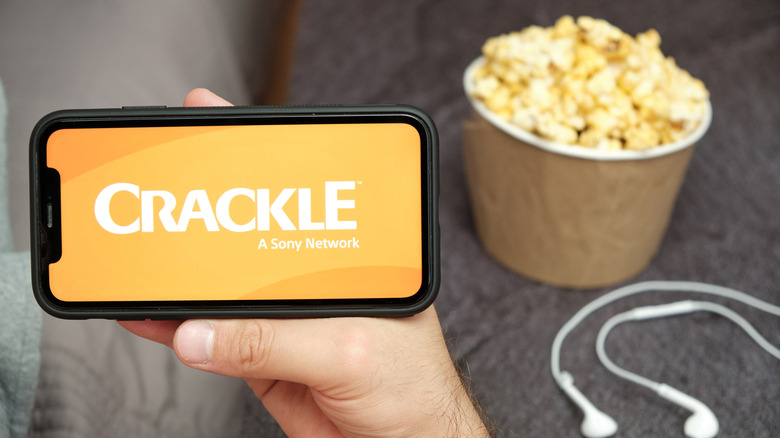 Crackle logo on smartphone, alongside popcorn and earbuds