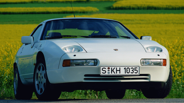 A white Porsche 928 in a grassy field.